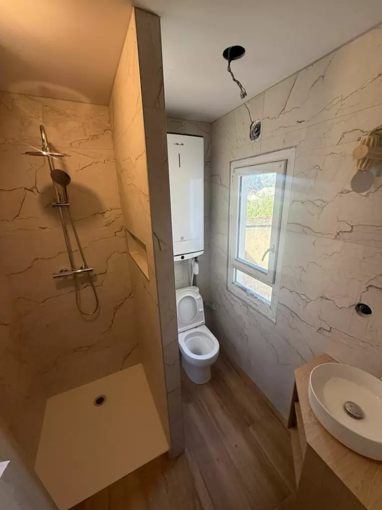 Salle d’eau avec douche à colonne thermostatique, WC, chauffe-eau mural et vasque à poser
